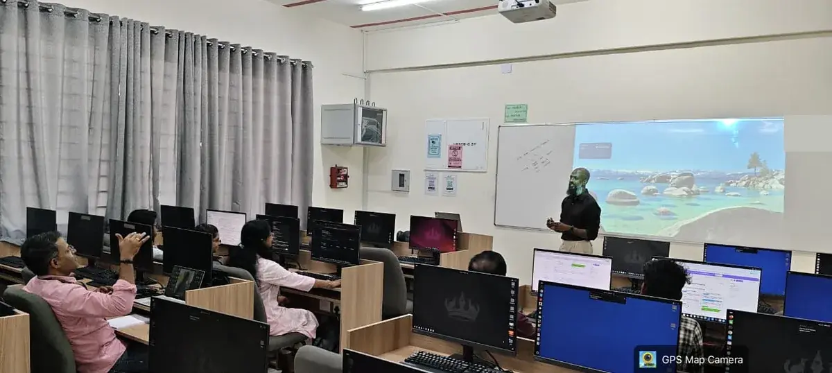 A facilitator speaking to faculty at computer workstations on Day 3
